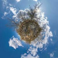 green tiny planet in blue sky with beautiful clouds with transformation of spherical panorama 360 degrees. Curvature of space. photo