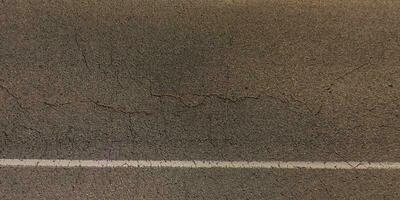 top view of surface of asphalt road made of small stones and sand with cracks photo