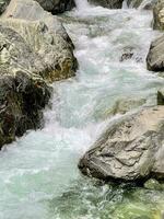 un Tormentoso corriente de un montaña río corriendo entre el piedras foto