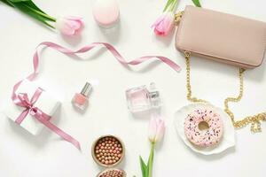 San Valentín día, madre día, primavera concepto con bolsa, rosquilla, tulipán rosado y productos cosméticos. parte superior vista. el ver desde el cima. tendencias concepto para un blogger foto