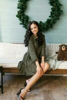 Photo of a positive lady sitting on a cozy sofa in a house indoors with a Christmas Christmas ornament