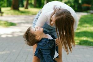 Mom and son are actively playing, having fun outdoors in the summer in the park. Happy motherhood, childhood, youth. Taking care of children. photo