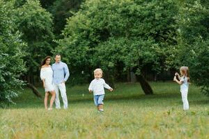 A young family with a son and daughter relax in the Park in the summer. They blow soap bubbles and have fun photo