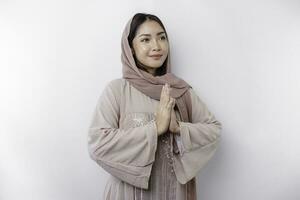 Portrait of a young beautiful Asian Muslim woman wearing a headscarf gesturing Eid Mubarak greeting photo