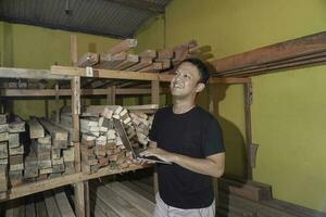 Handsome Asian Man is smiling while checking his carpentry workshop photo