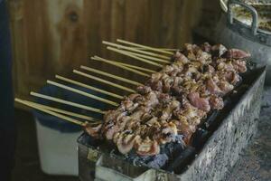 Sate Buntel or Satay Buntel is satay made from minced mutton wrapped in mutton fat is being grilled on charcoal photo