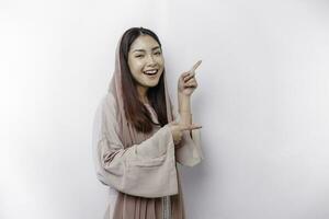 Young Asian Muslim woman smiling while pointing to copy space beside her photo