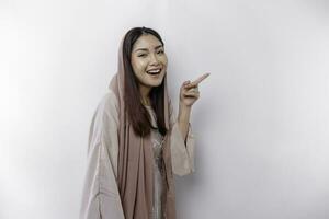 Young Asian Muslim woman smiling while pointing to copy space beside her photo