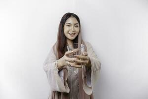 alegre asiático musulmán mujer vistiendo Pañuelo es Bebiendo un vaso de agua, aislado en blanco antecedentes. foto