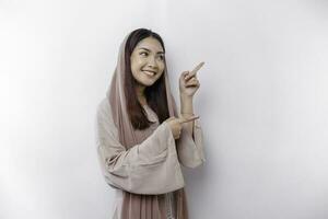 Young Asian Muslim woman smiling while pointing to copy space beside her photo