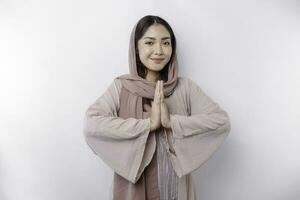 Portrait of a young beautiful Asian Muslim woman wearing a headscarf gesturing Eid Mubarak greeting photo