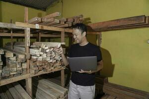 Handsome Asian Man is smiling while checking his carpentry workshop photo