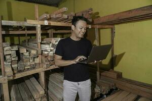 hermoso asiático hombre es sonriente mientras comprobación su carpintería taller foto