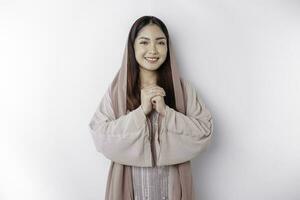 Portrait of a young beautiful Asian Muslim woman wearing a headscarf gesturing Eid Mubarak greeting photo