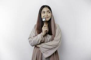 An Asian Muslim woman is fasting and hungry and holding cutlery while looking aside thinking about what to eat photo