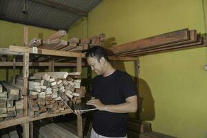 Handsome Asian Man is smiling while checking his carpentry workshop photo