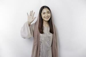 Portrait of a young beautiful Asian Muslim woman wearing a headscarf gesturing Eid Mubarak greeting photo