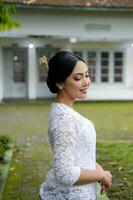 A young Indonesian woman with a happy successful expression wearing a white kebaya. Kartini's Day Concept. photo