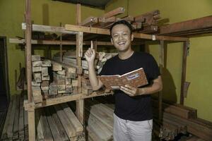 Handsome Asian Man is smiling while checking his carpentry workshop photo