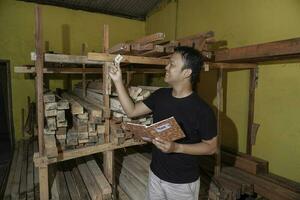 Handsome Asian Man is smiling while checking his carpentry workshop photo