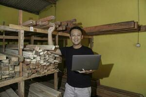 Handsome Asian Man is smiling while checking his carpentry workshop photo