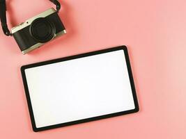 flat lay of digital tablet with blank white screen and digital camera isolated on pink background. photo