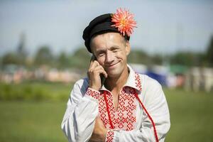 08 29 2020 Belarus, Lyaskovichi. Celebration in the city. An elderly Slavic man in an embroidered shirt speaks on the phone. photo