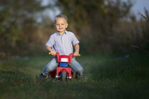 Little boy rides a red bike in summer. photo