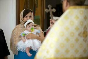 bielorrusia, el ciudad de gomel junio 15, 2020. ciudad iglesia. bautismo de el niño. madre sostiene el bebé en su brazos durante el bautismo ceremonia. adoptar un religión foto