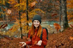 alegre mujer viajes en el otoño bosque en naturaleza cerca el río y alto arboles en el antecedentes foto