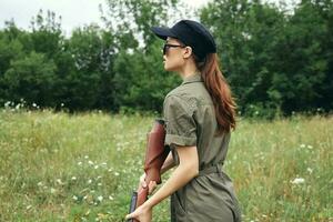 Military woman with a gun hunting green overalls green leaves green photo