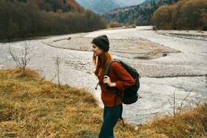 woman in autumn in the mountains with a backpack on her shoulders travel tourism river photo