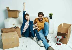 casado Pareja hombre y mujer en de madera piso con cajas Moviente flor en un maceta reparar trabajo foto