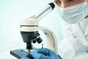 woman looking through a microscope diagnostics science research close-up photo