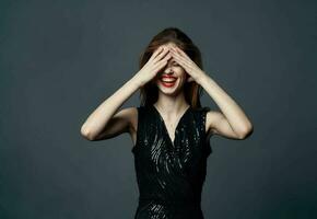 Emotional woman touches her head with hands and black dress model gray background photo