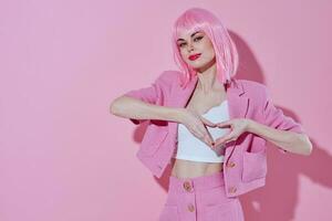 hermosa de moda niña sostener manos en el forma de un corazón con un rosado chaqueta rosado antecedentes foto