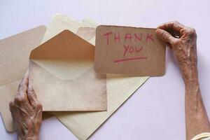 mano de mujer mayor sosteniendo carta de agradecimiento, vista trasera foto