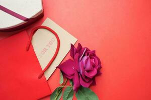 Top view of gift box and rose flower on color background photo