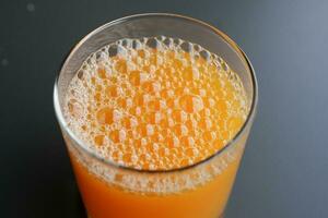 glass of orange juice with bubble on table photo