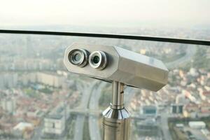 Coin-operated binoculars looking out over city , photo