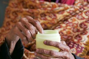 elderly woman using petroleum jelly onto skin photo