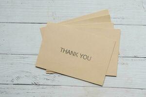 thank you message and envelope on wooden table photo