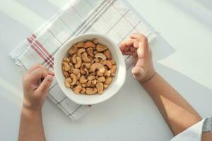 child hand pick cashew nuts in a bowl photo