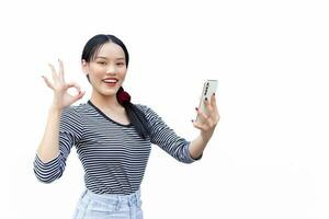 Portrait of cute Asian Thai girl student looking friendly is holding smartphone standing smiling happily and confidently successful showing for communication as okey to present something photo