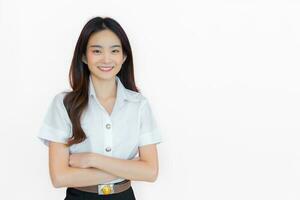 retrato de adulto tailandés alumno. hermosa asiático joven mujer estudiante en uniforme es sonriente y mirando a cámara con su brazos cruzado con confianza en blanco antecedentes en el Universidad foto