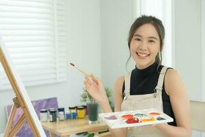 beautiful female hobbies about artist and use paintbrush in abstract art for create masterpiece. painter paint with watercolors or oil in studio house. enjoy painting as hobby, recreation, inspiration photo