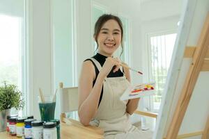 beautiful female hobbies about artist and use paintbrush in abstract art for create masterpiece. painter paint with watercolors or oil in studio house. enjoy painting as hobby, recreation, inspiration photo