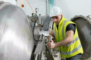 ingenieros o fábrica gerentes vistiendo la seguridad casco inspeccionar el máquinas en el producción línea. utilidad inspector cheque máquina y prueba el sistema a reunirse el estándar. máquina, mantenimiento. foto