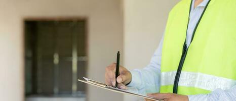 el inspector o ingeniero está inspeccionando la construcción y el aseguramiento de la calidad de la nueva casa usando una lista de verificación. ingenieros o arquitectos o contratistas trabajan para construir la casa antes de entregársela al propietario foto