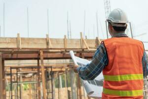inspector or engineer is inspecting construction and quality assurance new house using a blue print. Engineer or architects or contactor work to build the house before handing it over to the homeowner photo